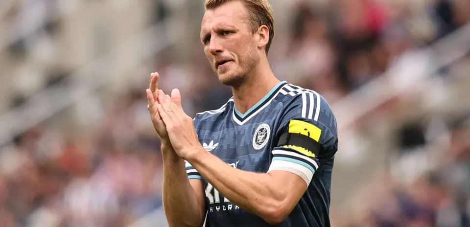 Player applauding fans while wearing captain's armband