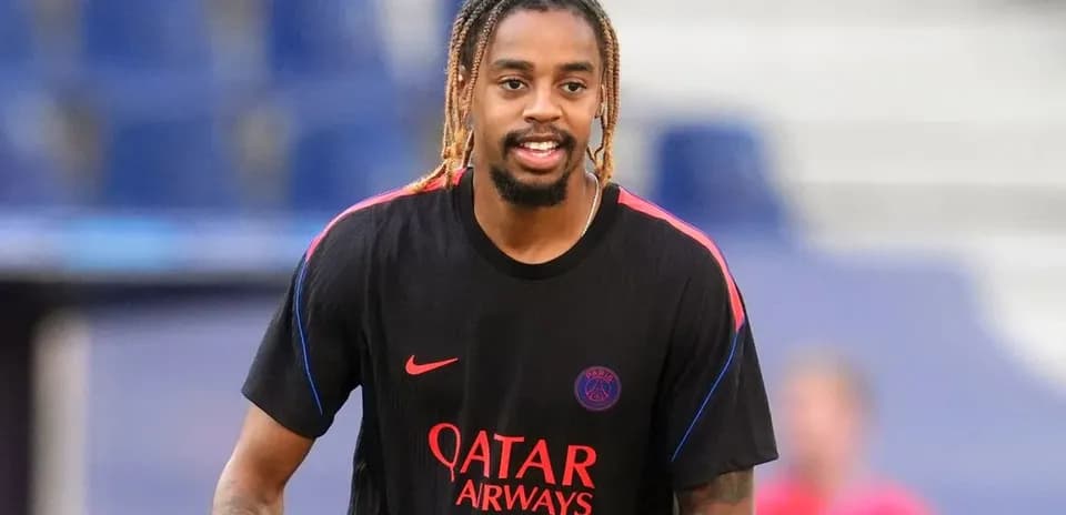 Player in PSG training kit smiling on pitch