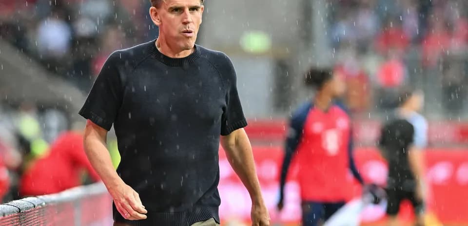 Coach walking along sideline during rainy match