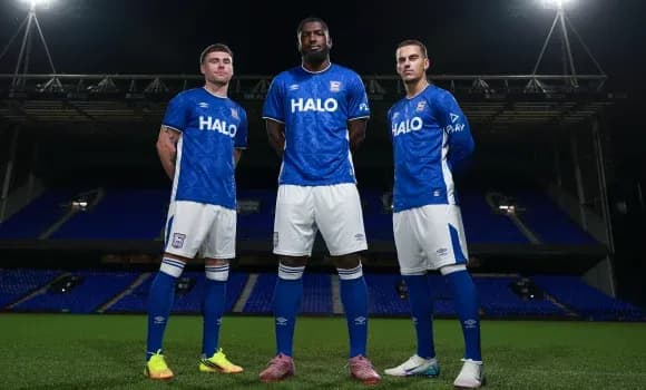 Three players in blue kits standing on pitch