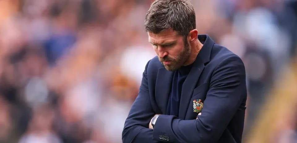 Coach with arms crossed looking down during match