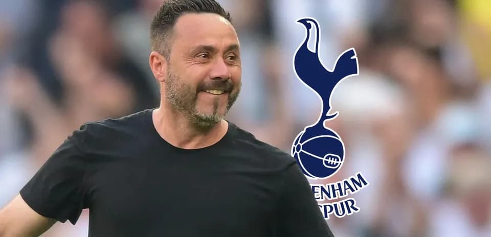 Manager smiling on the pitch with Tottenham logo