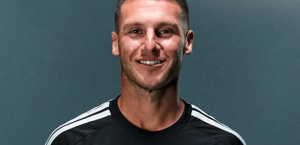 Player in black kit smiling for photo