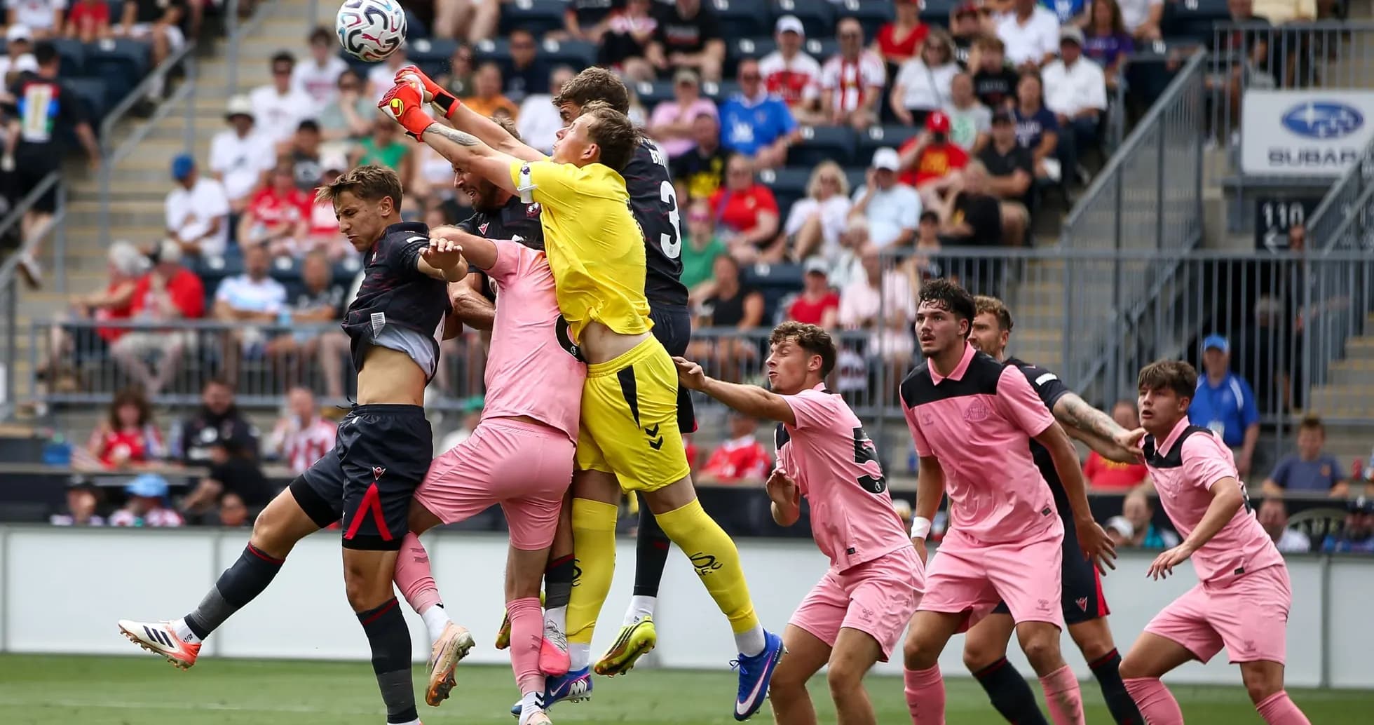 Goalkeeper jumping to catch the ball amid players