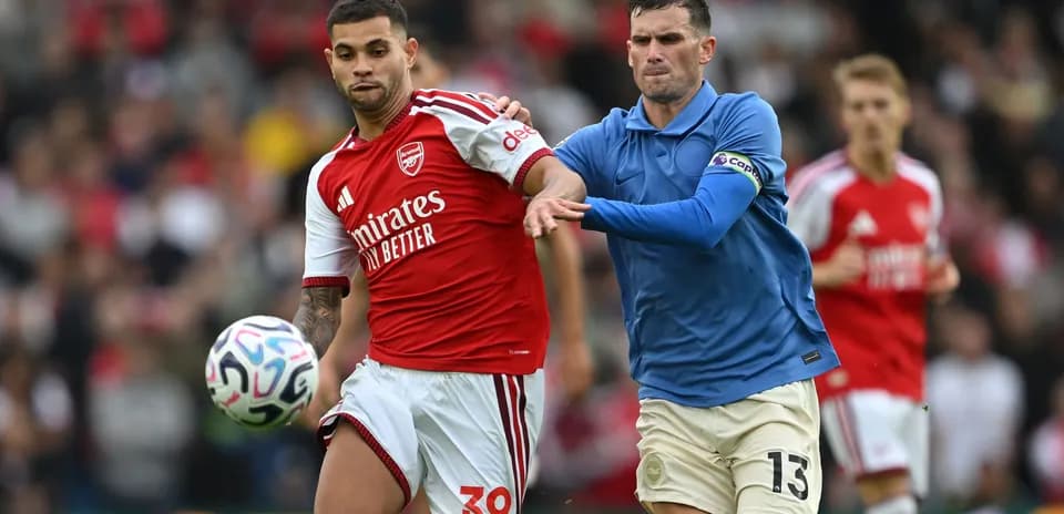 Player in red dribbling past opponent in blue