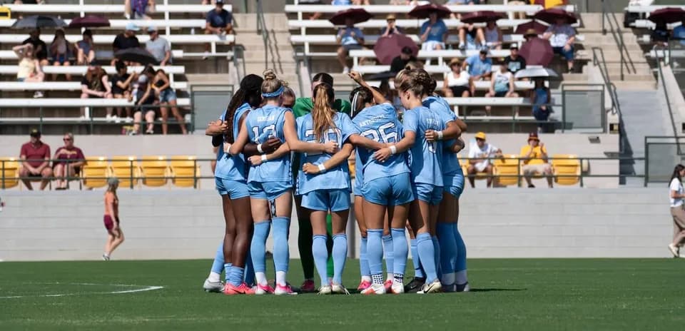 Team huddling together on the soccer field