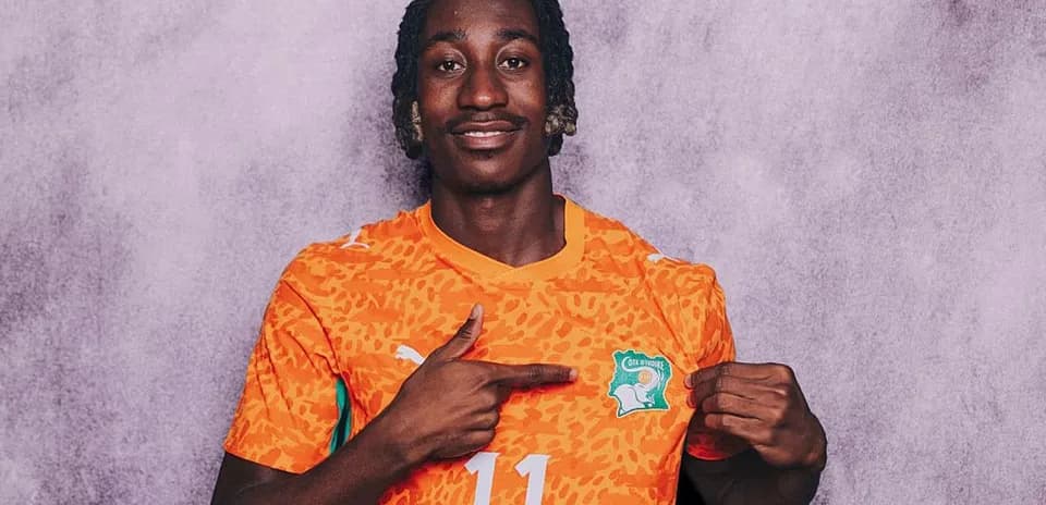 Player in orange jersey pointing at team badge
