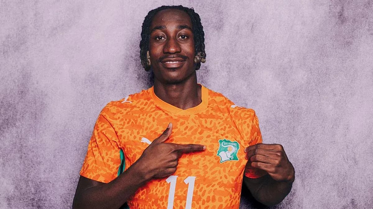 Player in orange jersey pointing at team badge