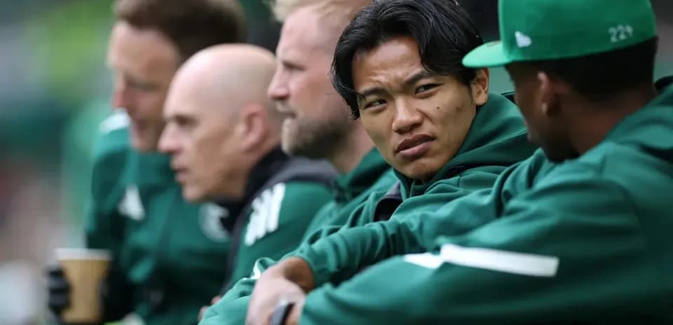Coaches and players seated on bench during match