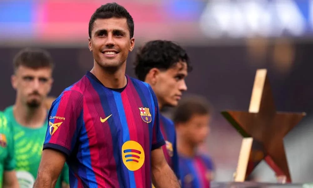 Player smiling while holding a trophy on pitch