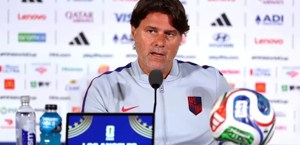 Coach speaking at press conference with soccer ball
