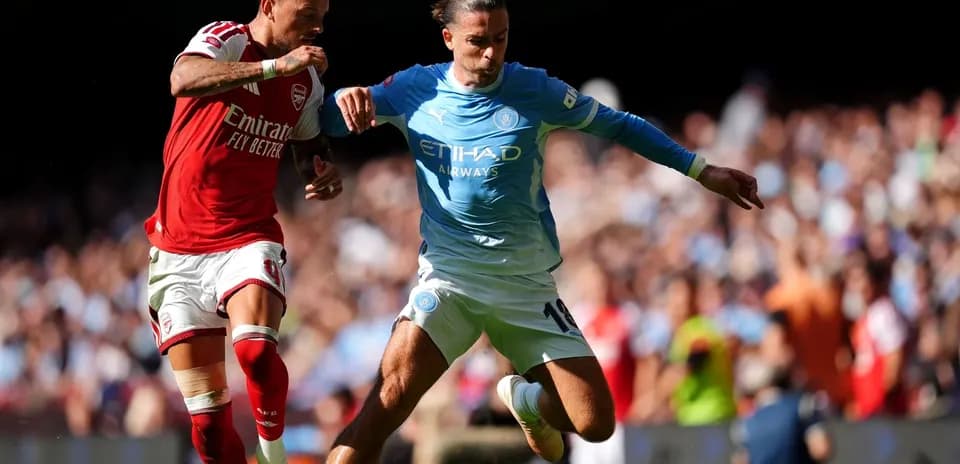 Player from Arsenal challenges Manchester City player for ball