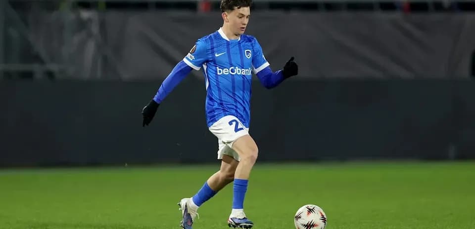 Player in blue kit kicking soccer ball on field