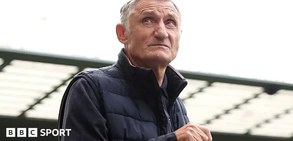 Man in a vest holding a bottle at stadium