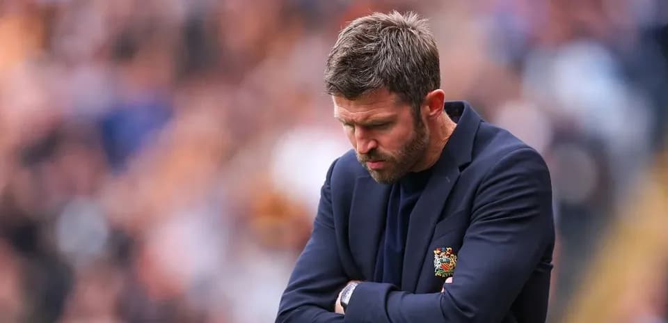 Coach with arms crossed, looking down during match