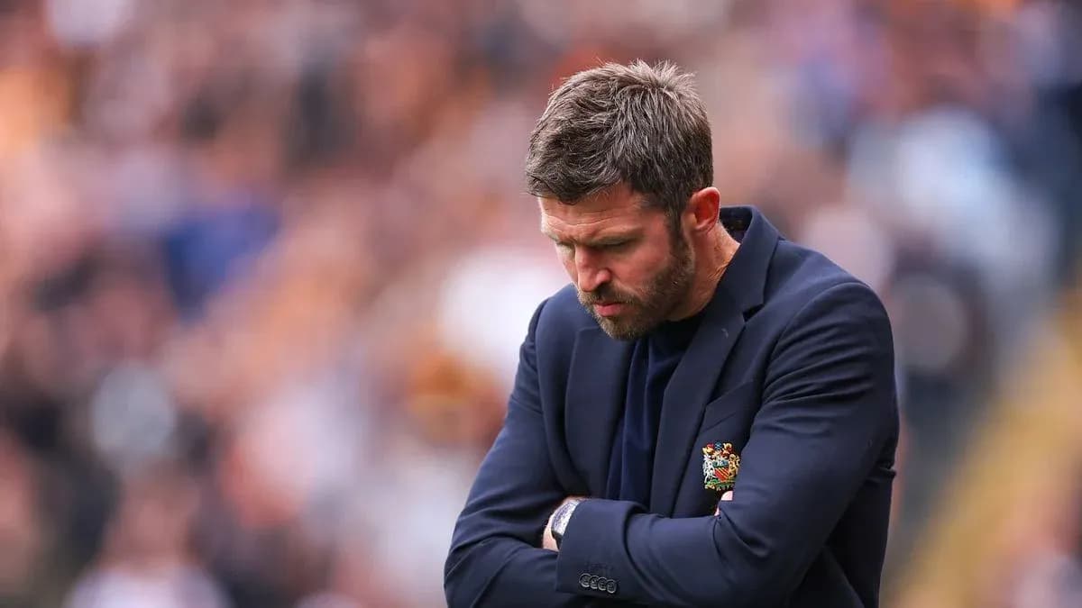 Coach with arms crossed, looking down during match