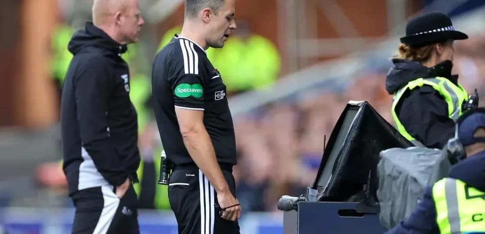 Referee reviewing play at VAR monitor during match