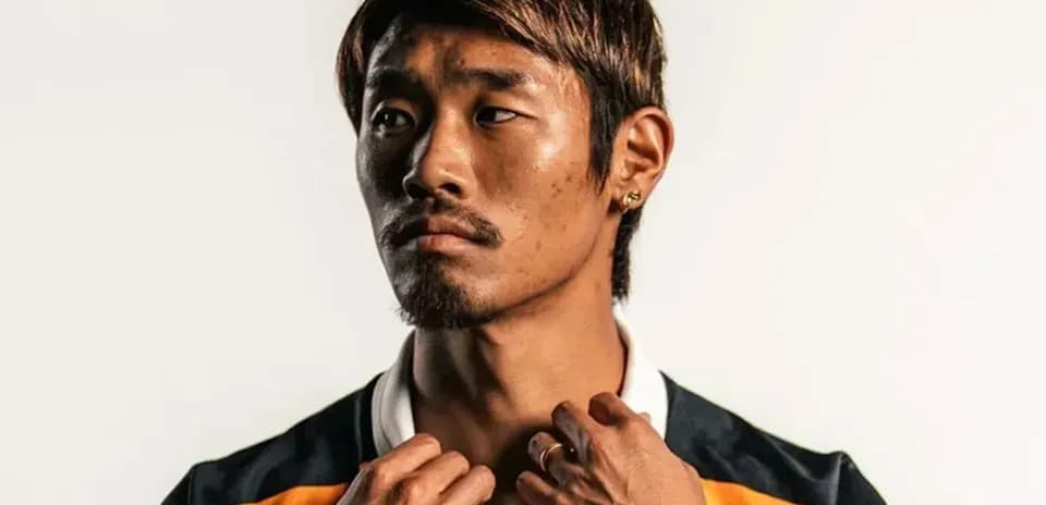 Player posing in sports jersey against plain background