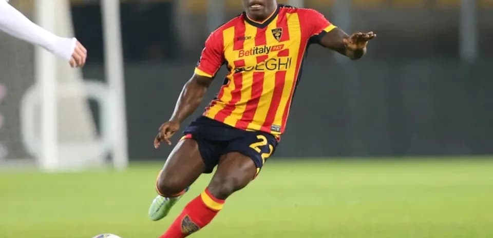 Player in yellow and red kit dribbling ball on field