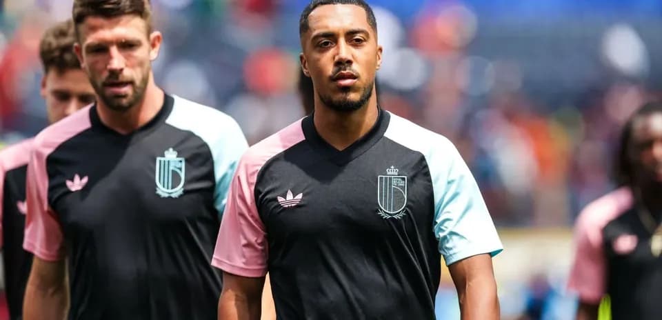 Players walking on the pitch in warm-up jerseys