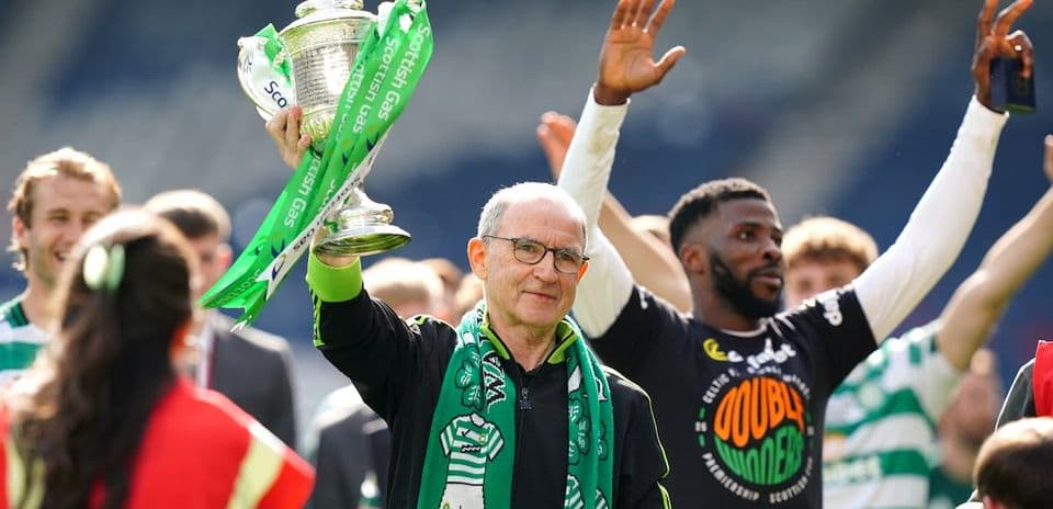 Man holding trophy with celebratory crowd behind