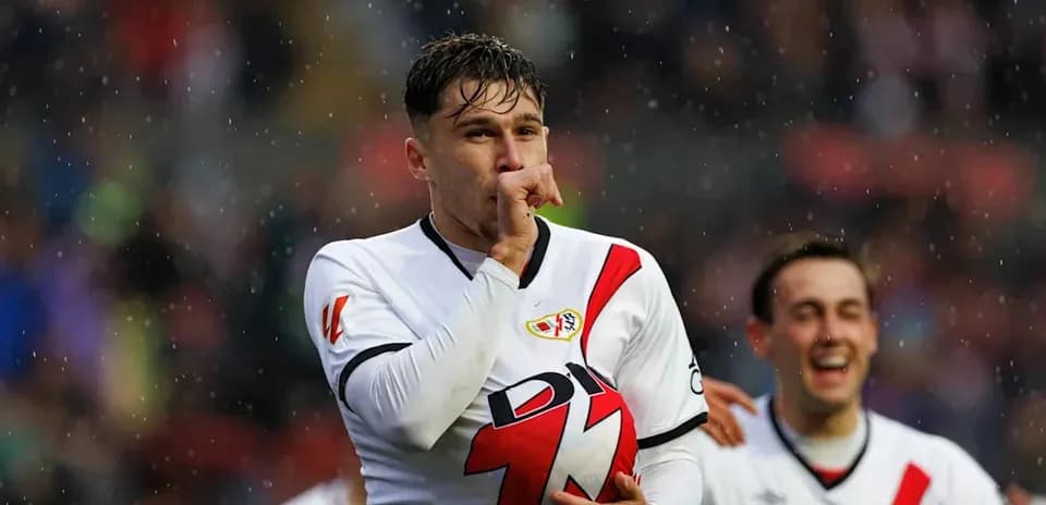 Player celebrating a goal with teammates in rain