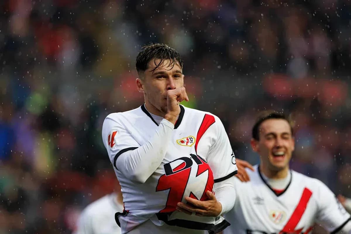 Player celebrating a goal with teammates in rain