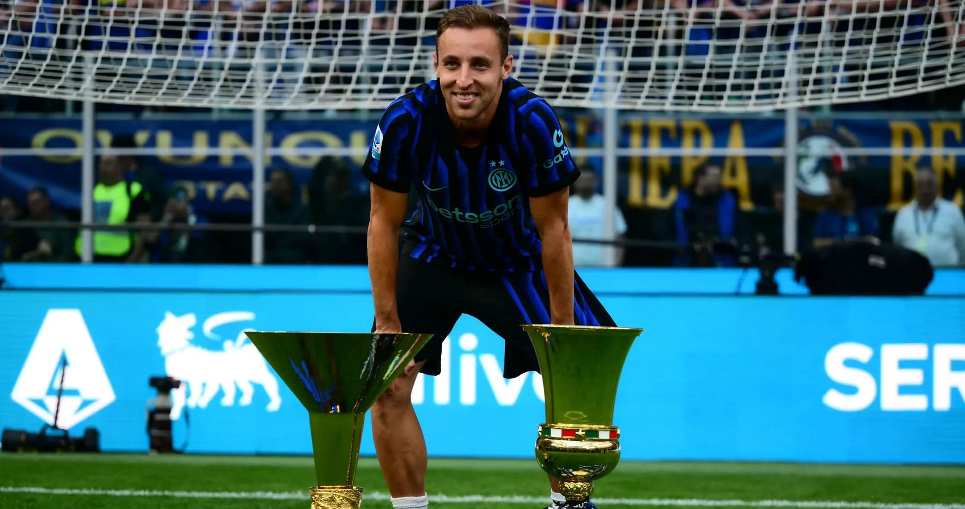 Player celebrating with two trophies on the field