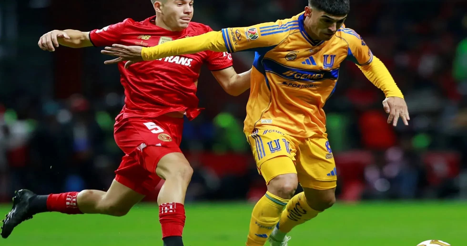 Toluca player challenging Tigres UANL player