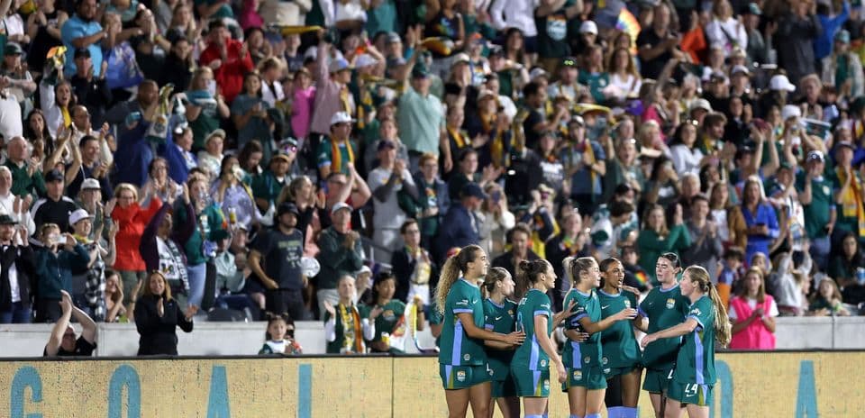 Players celebrating a goal with cheering crowd
