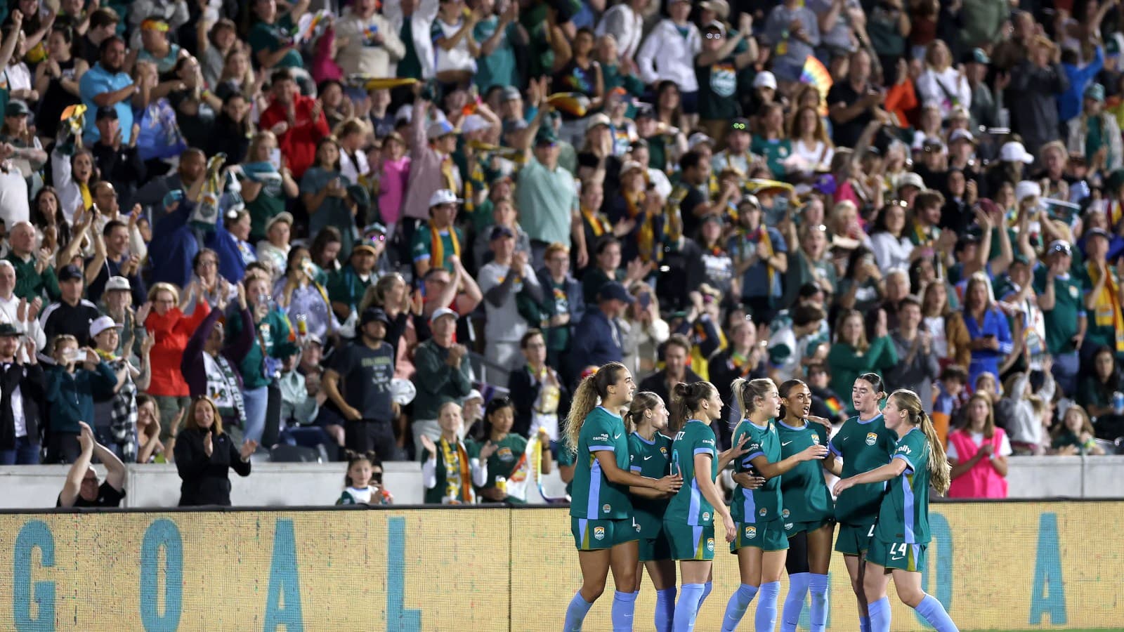 Players celebrating a goal with cheering crowd