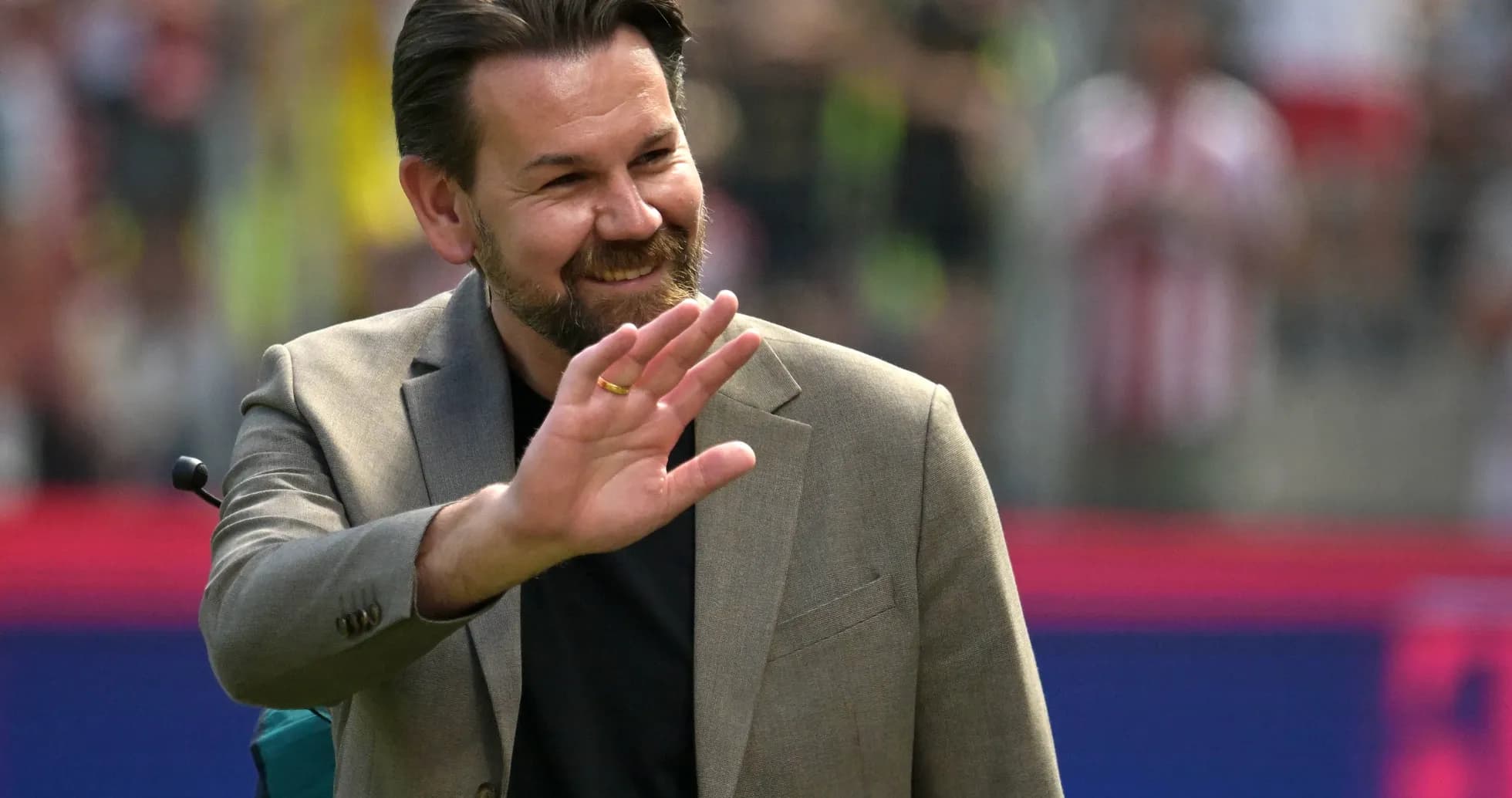 Man in suit waving at crowd during event