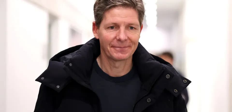 Man walking in a corridor wearing a dark coat
