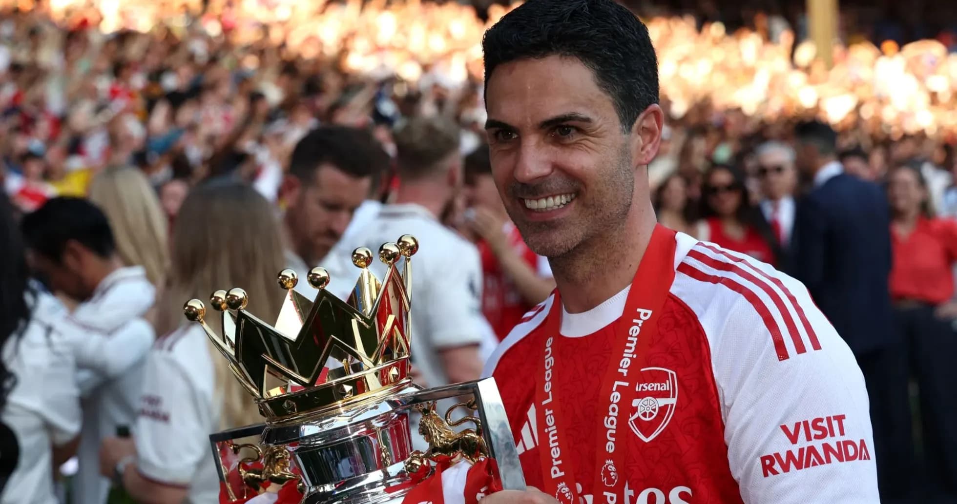 Arsenal manager holding Premier League trophy in celebration