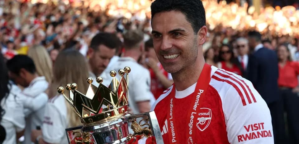 Arsenal manager holding Premier League trophy in celebration