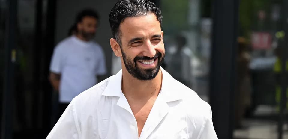 Man smiling while wearing a white shirt outdoors
