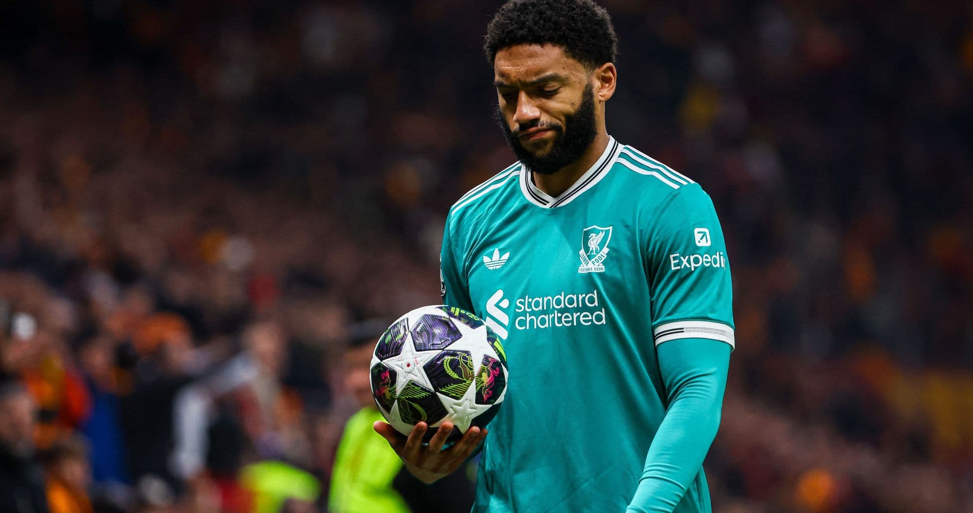 Player in Liverpool kit holding football on pitch