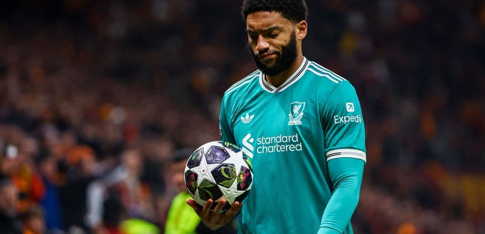 Player in Liverpool kit holding football on pitch