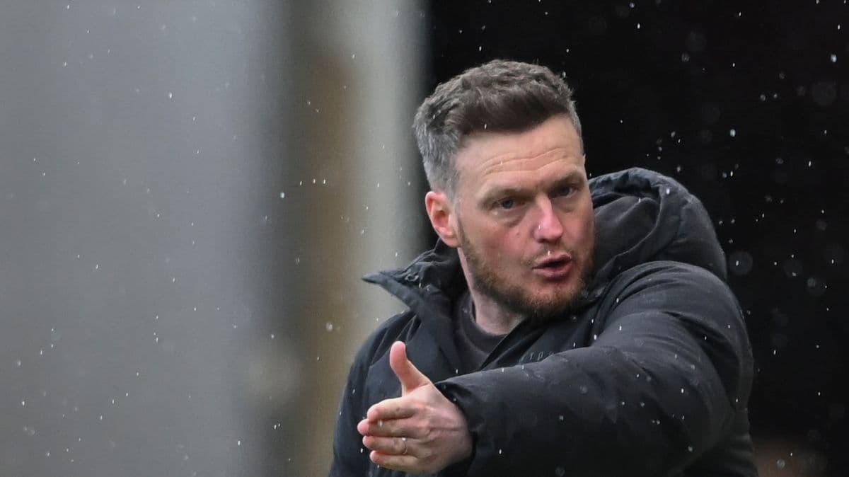 Coach gesturing during match in rainy weather