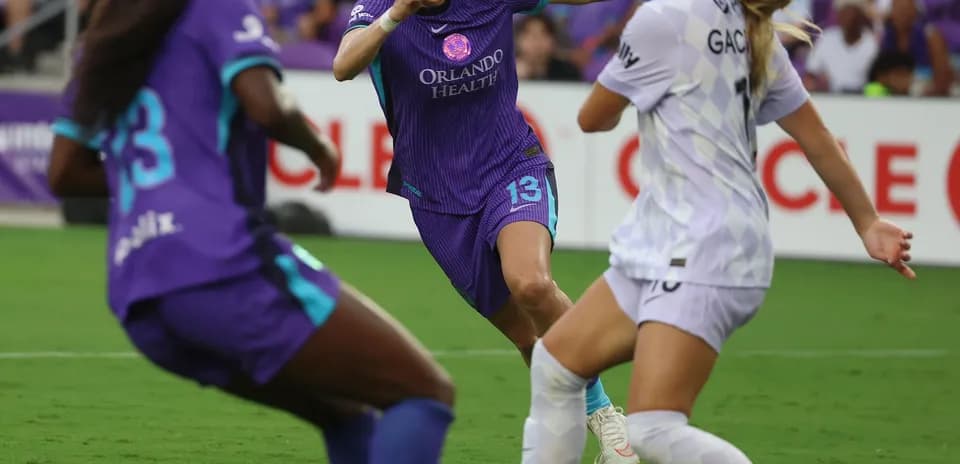 Orlando Pride player challenging Portland Thorns opponent