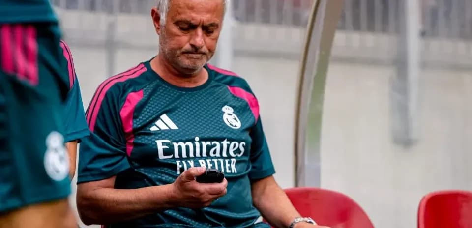 Coach sitting on bench checking phone during match