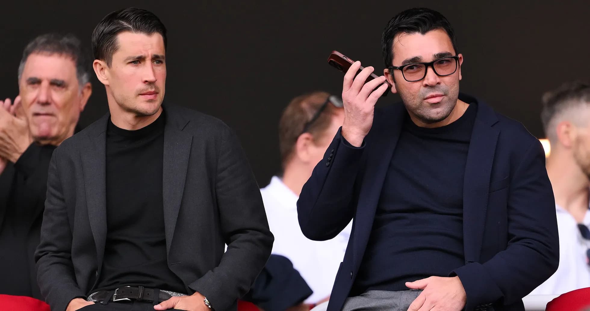 Two men seated in stands during event