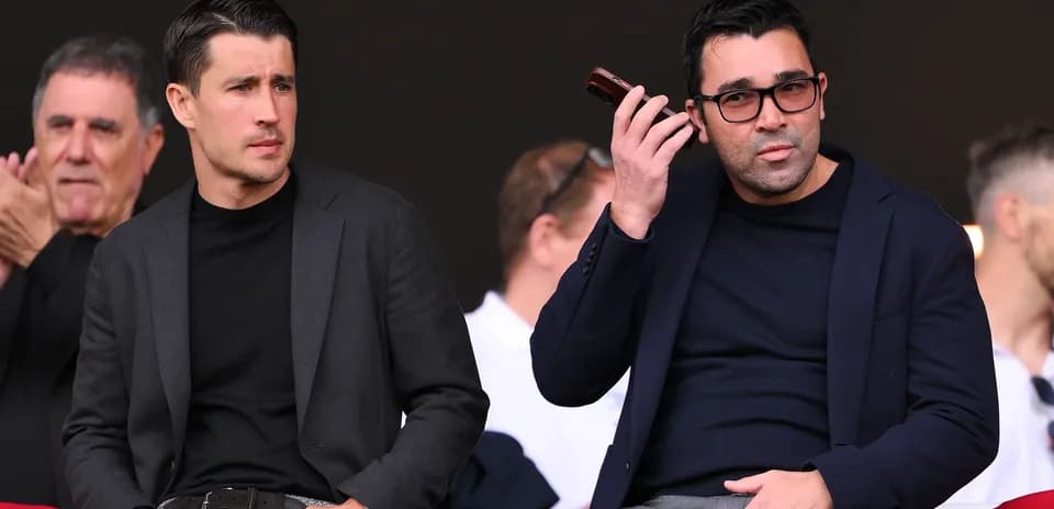 Two men seated in stands during event