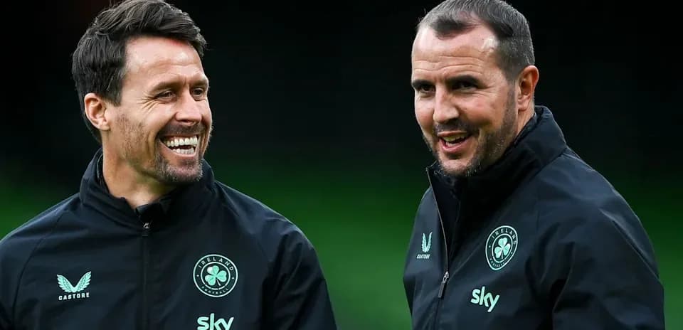 Two coaches smiling and conversing during training