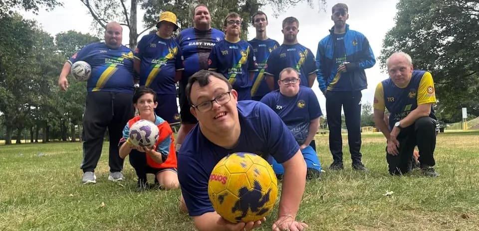 Group of players posing with soccer balls outdoors