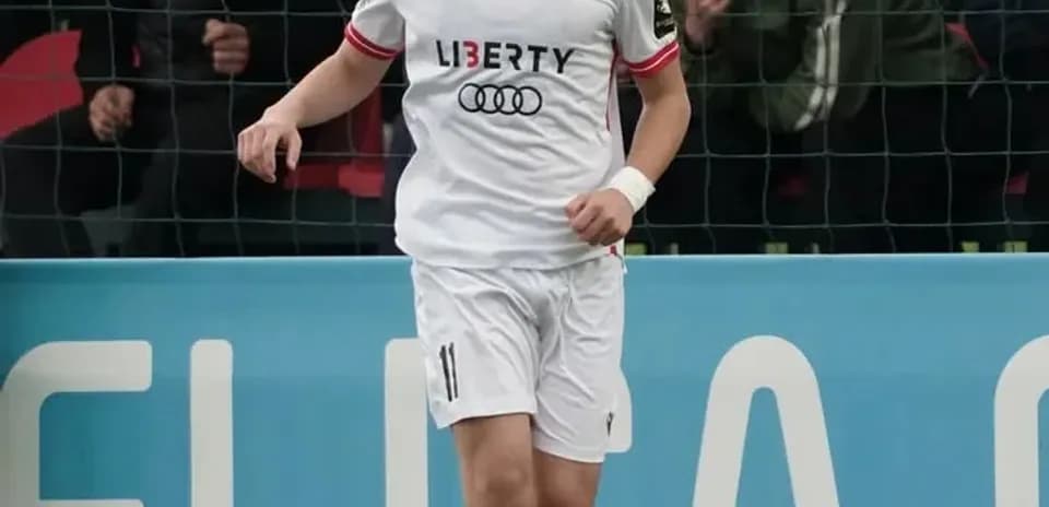 Player in white kit dribbling ball on field