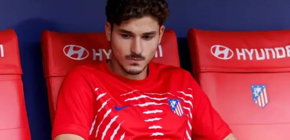 Player sitting on bench wearing Atletico Madrid kit