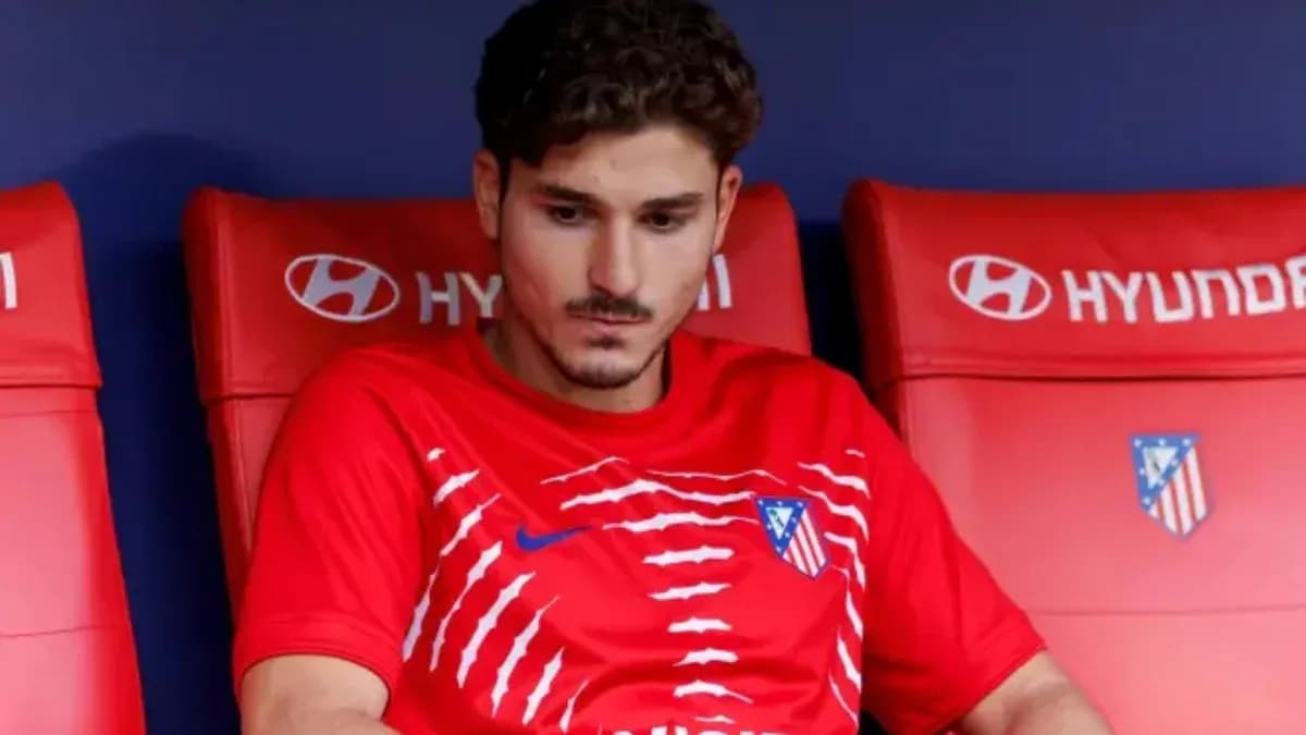 Player sitting on bench wearing Atletico Madrid kit