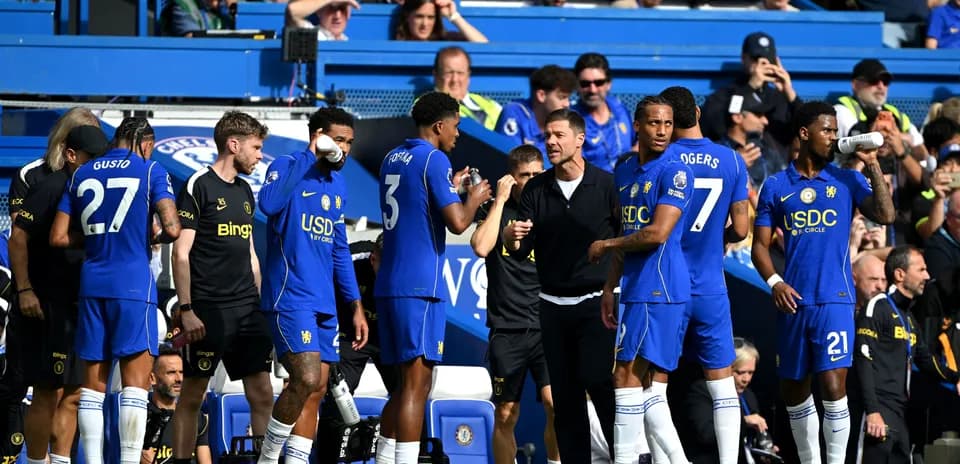 Chelsea players and coach discussing strategy on sideline
