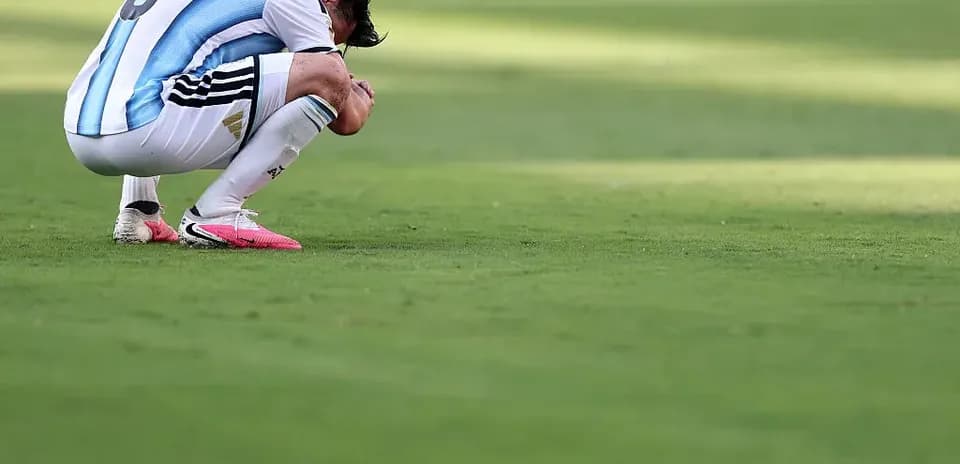 Player kneeling on pitch with head down